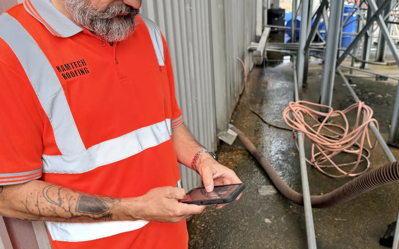 Ramtech estimator documenting roof findings on a phone during an on-site assessment.