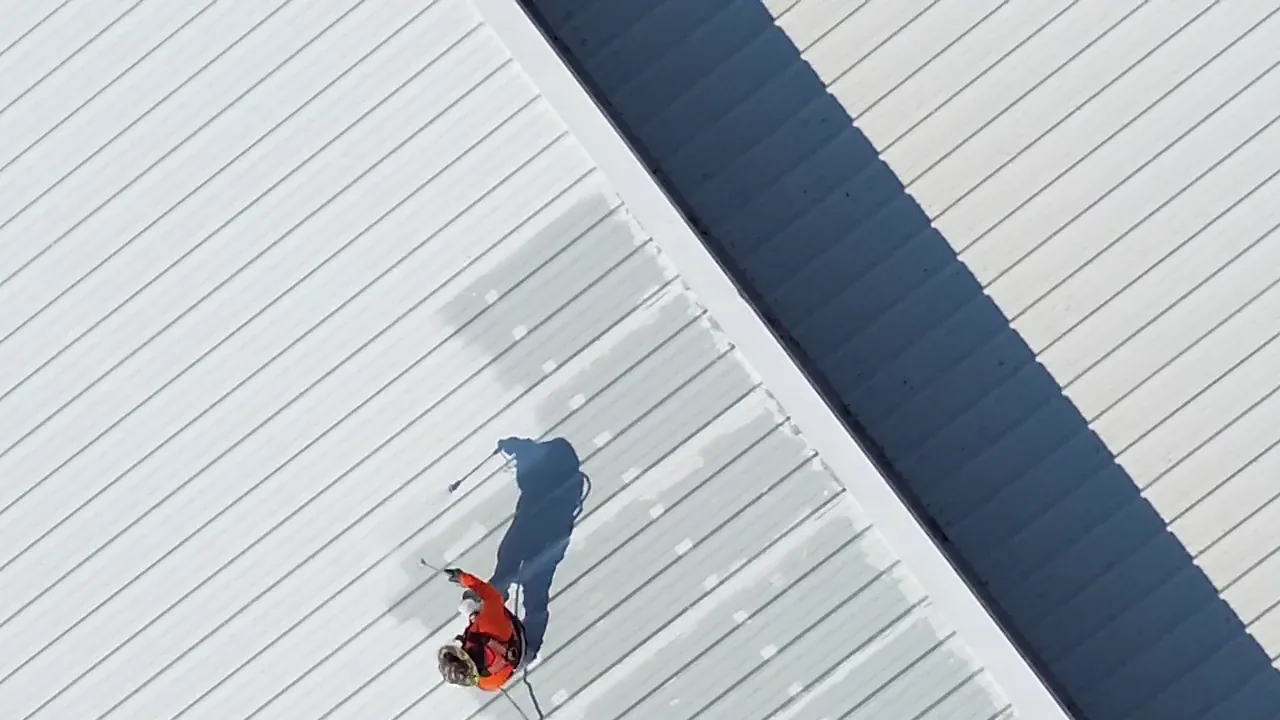 Ramtech crew member preparing seams on an aged metal panel roof before restoration