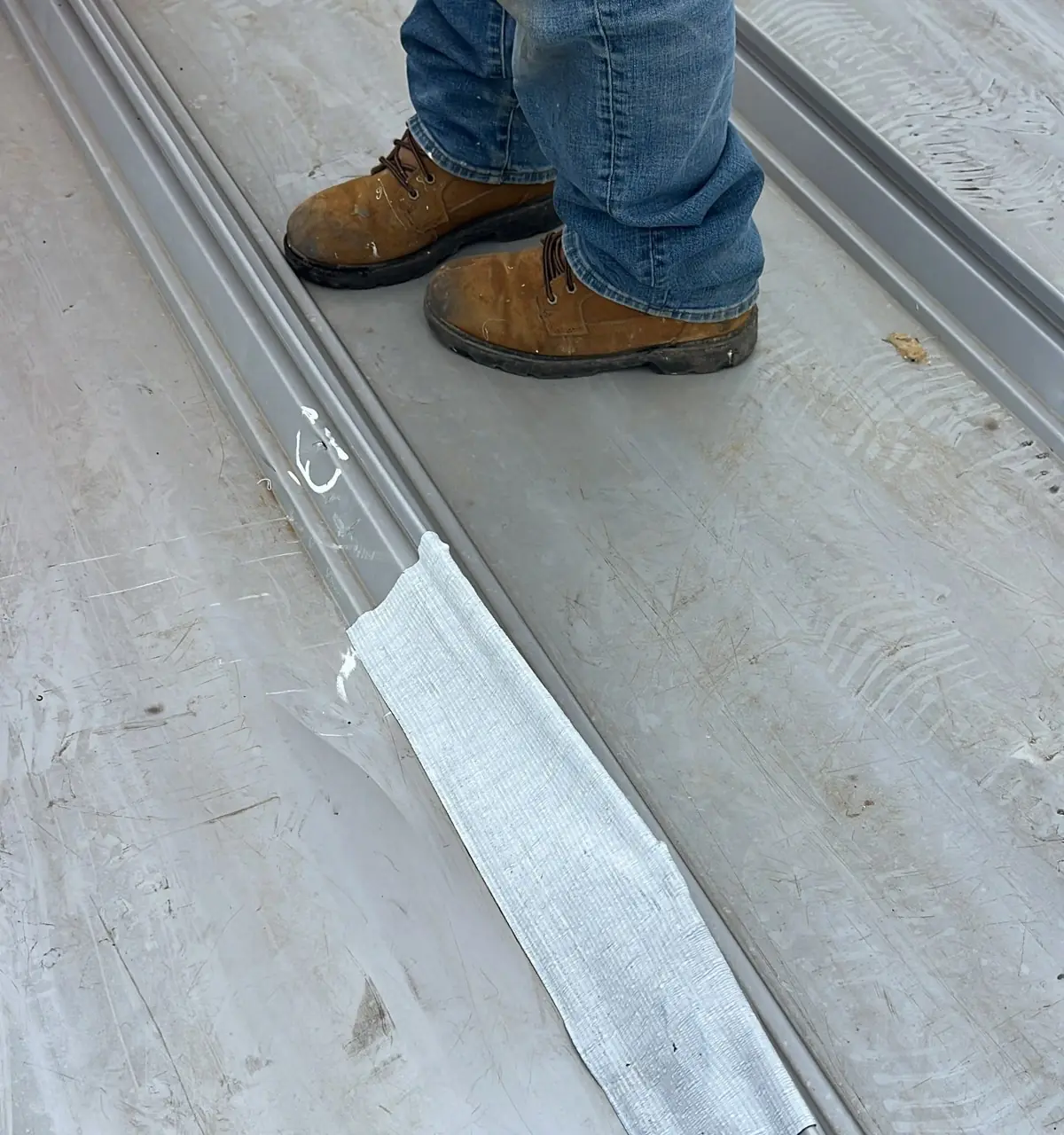 Fabric-reinforced fluid-applied repair over a metal roof seam