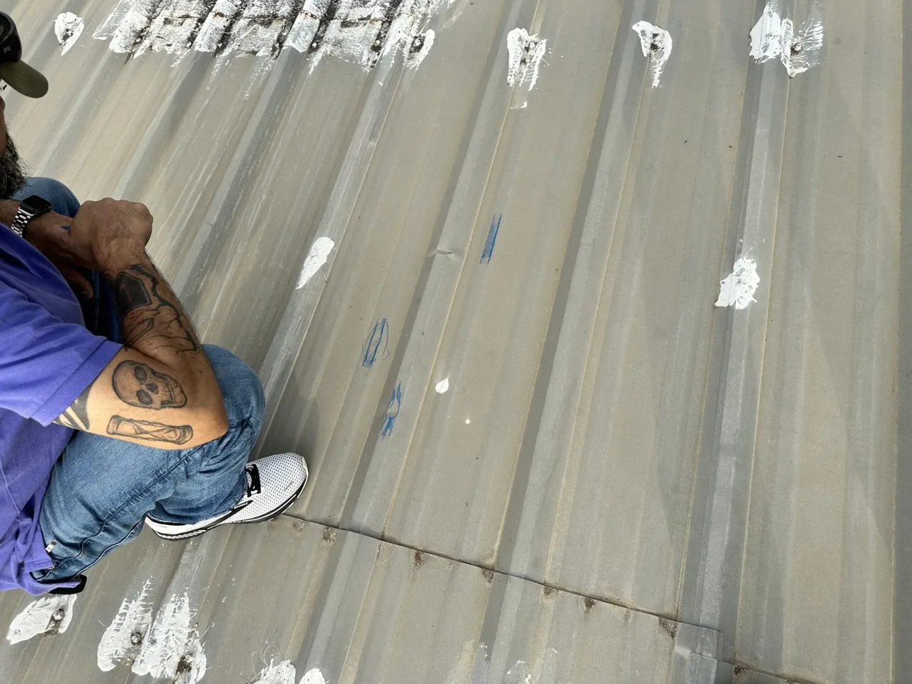 Roofer preparing seams and fasteners on a weathered metal roof before restoration