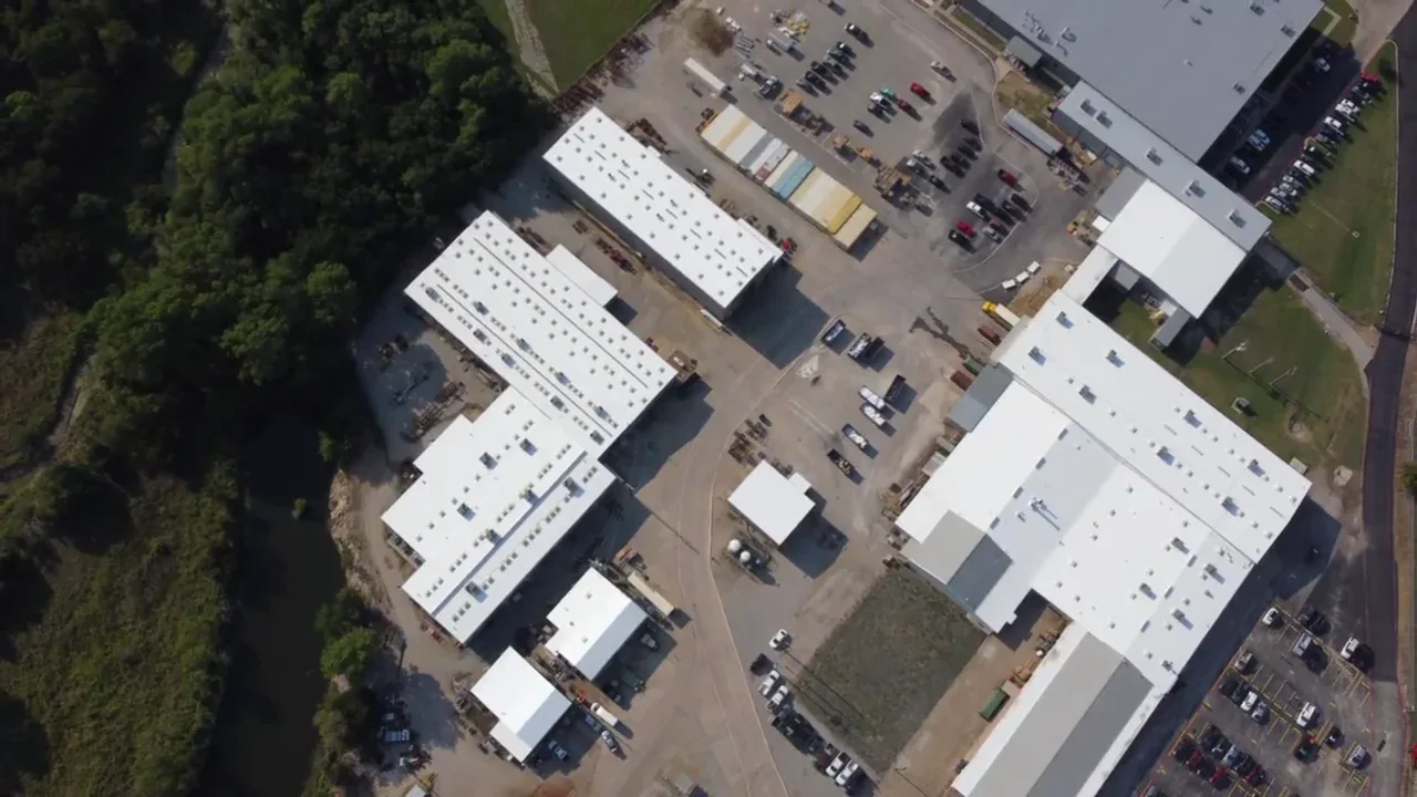 Aerial view of a completed white silicone restoration over an aged PVC industrial roof