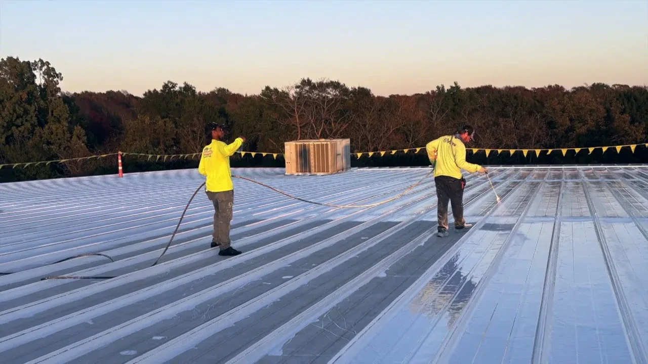 Crew applying silicone across a metal roof section on a multi-system industrial restoration