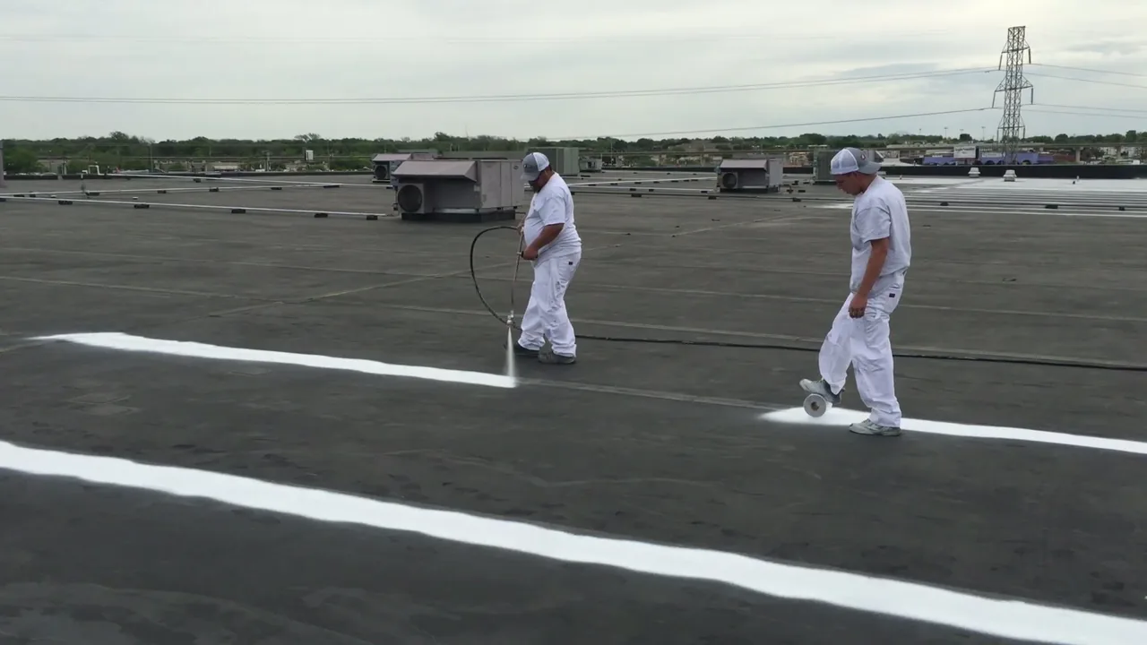 Ramtech crew spray-applying a white silicone roof coating on a low-slope commercial roof