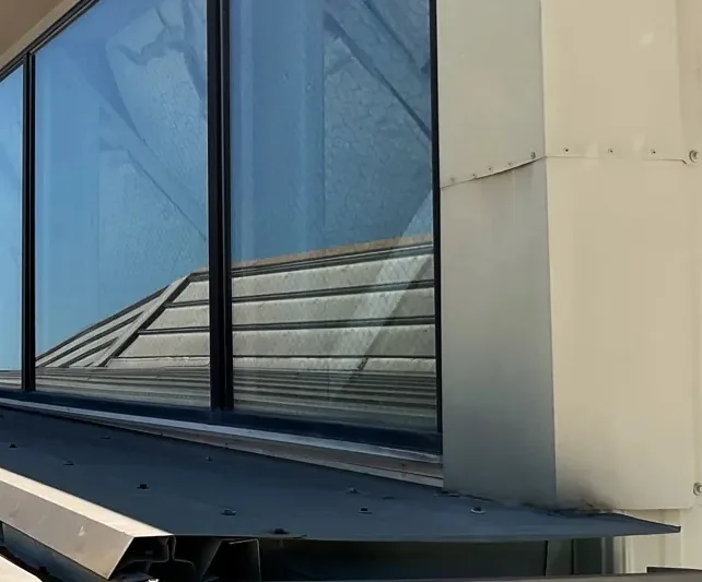 Before: open, weathered flashing at a clerestory window on a commercial metal roof.