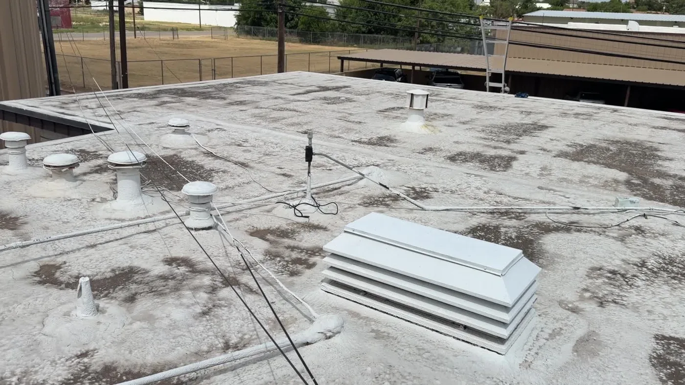 Weathered low-slope commercial roof with vents and rooftop equipment in Ballinger, Texas