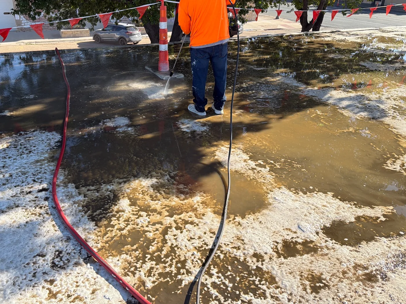 Rinse water and loosened dirt across a commercial roof during cleaning in Ballinger, Texas