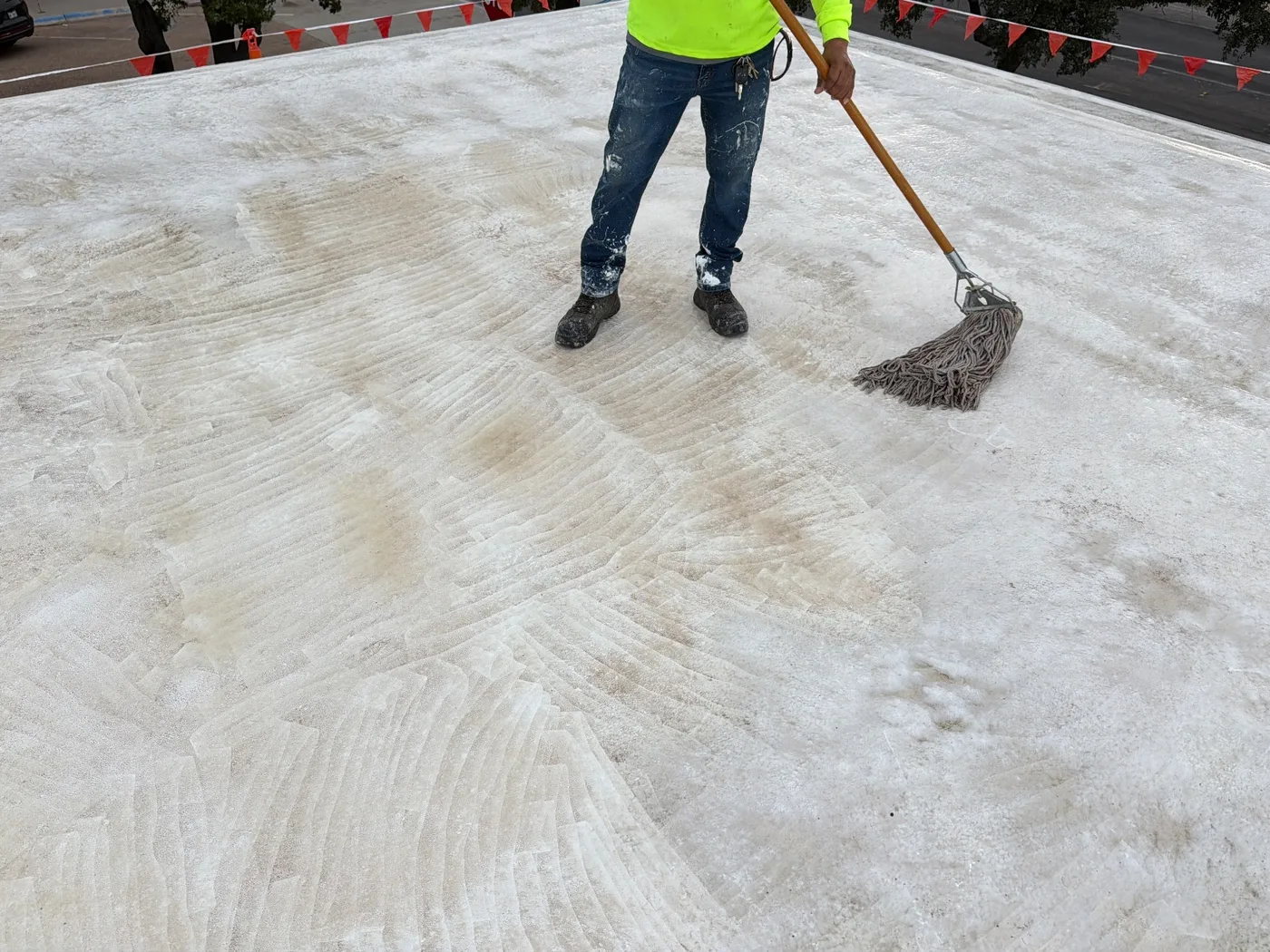 Crew member working the cleaned roof surface by hand in Ballinger, Texas