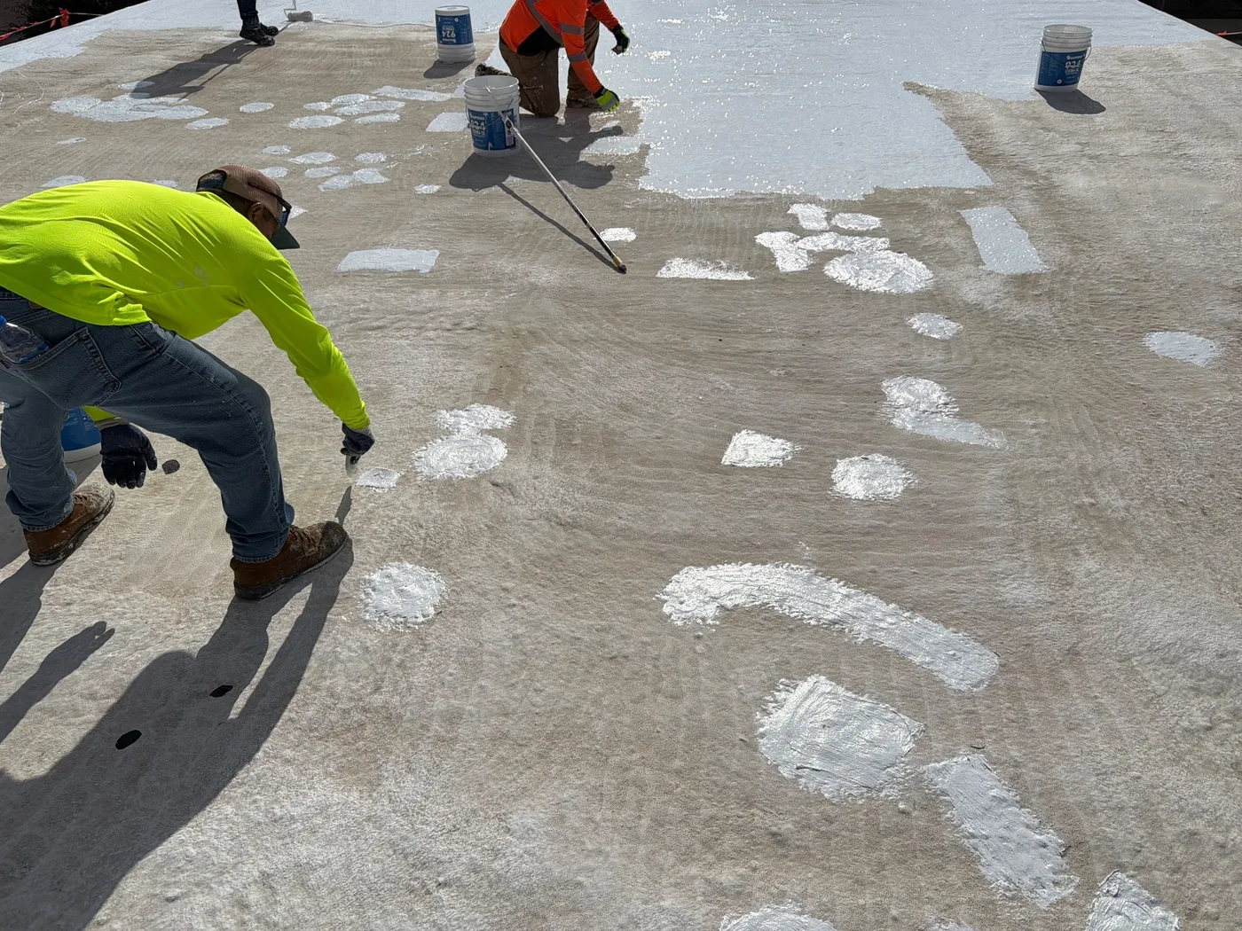 Crew brushing white spot details across a commercial roof in Ballinger, Texas