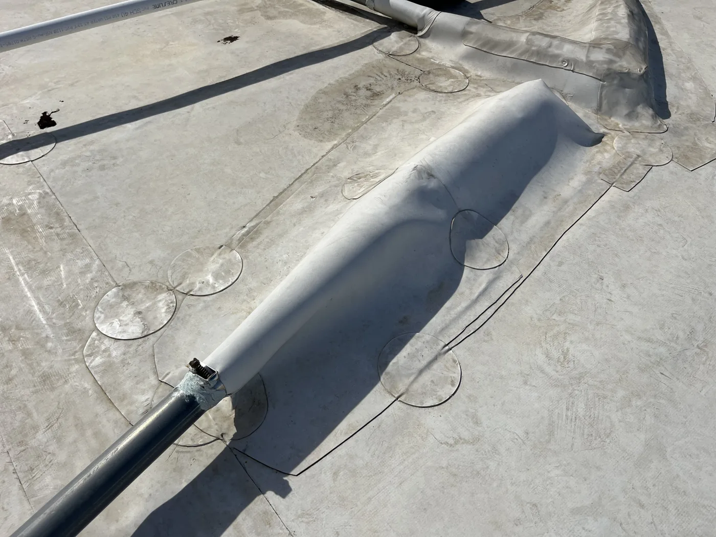 Wrinkled, aged TPO seam on a low-slope commercial roof before restoration