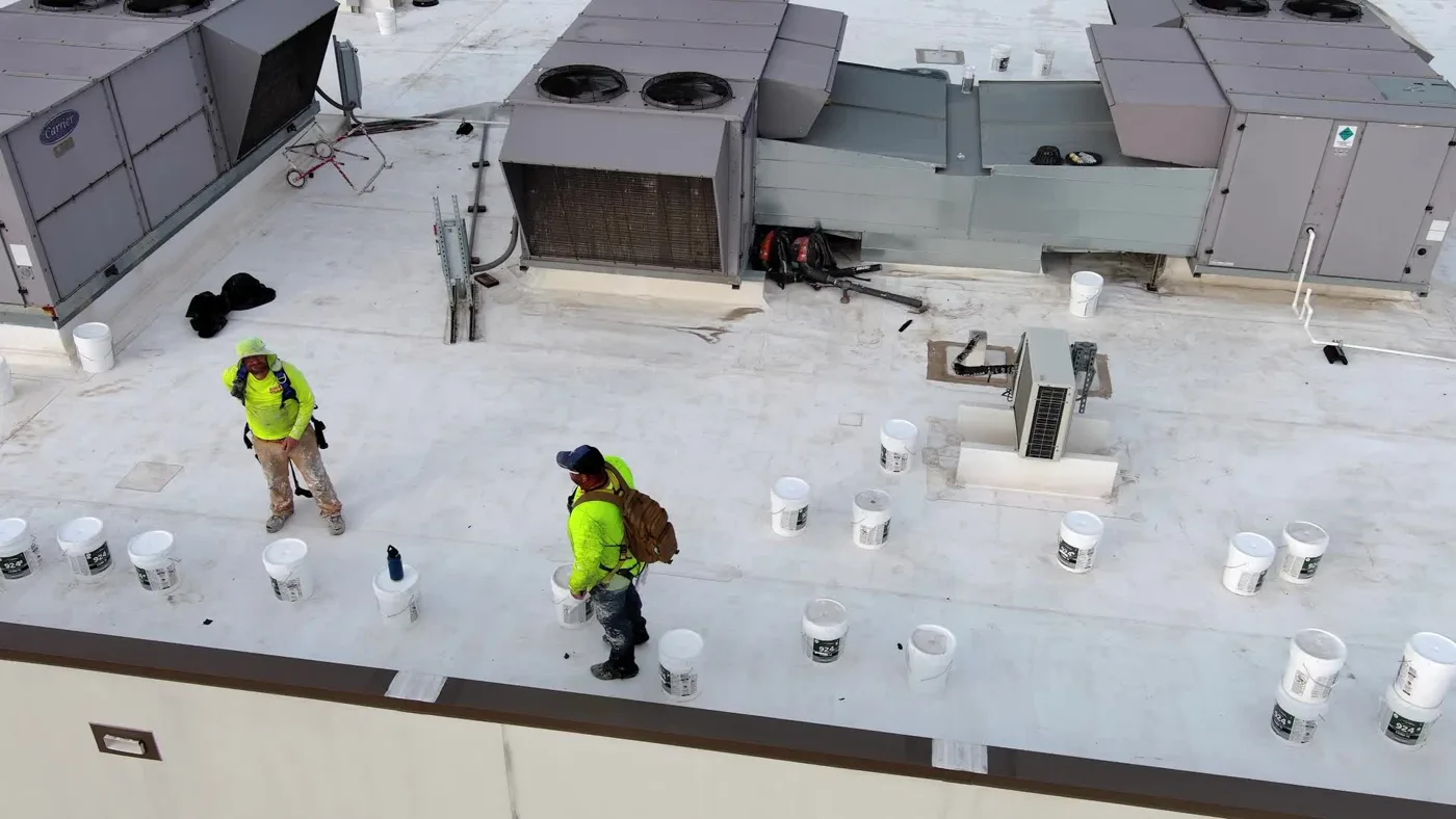 Ramtech crew members working on a white silicone roof among rooftop units