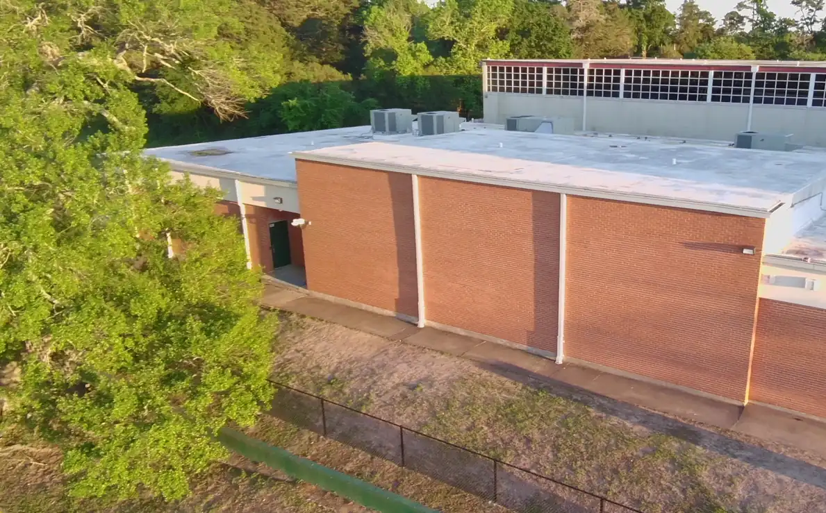 Drone view of a brick school band hall and its low-slope roof