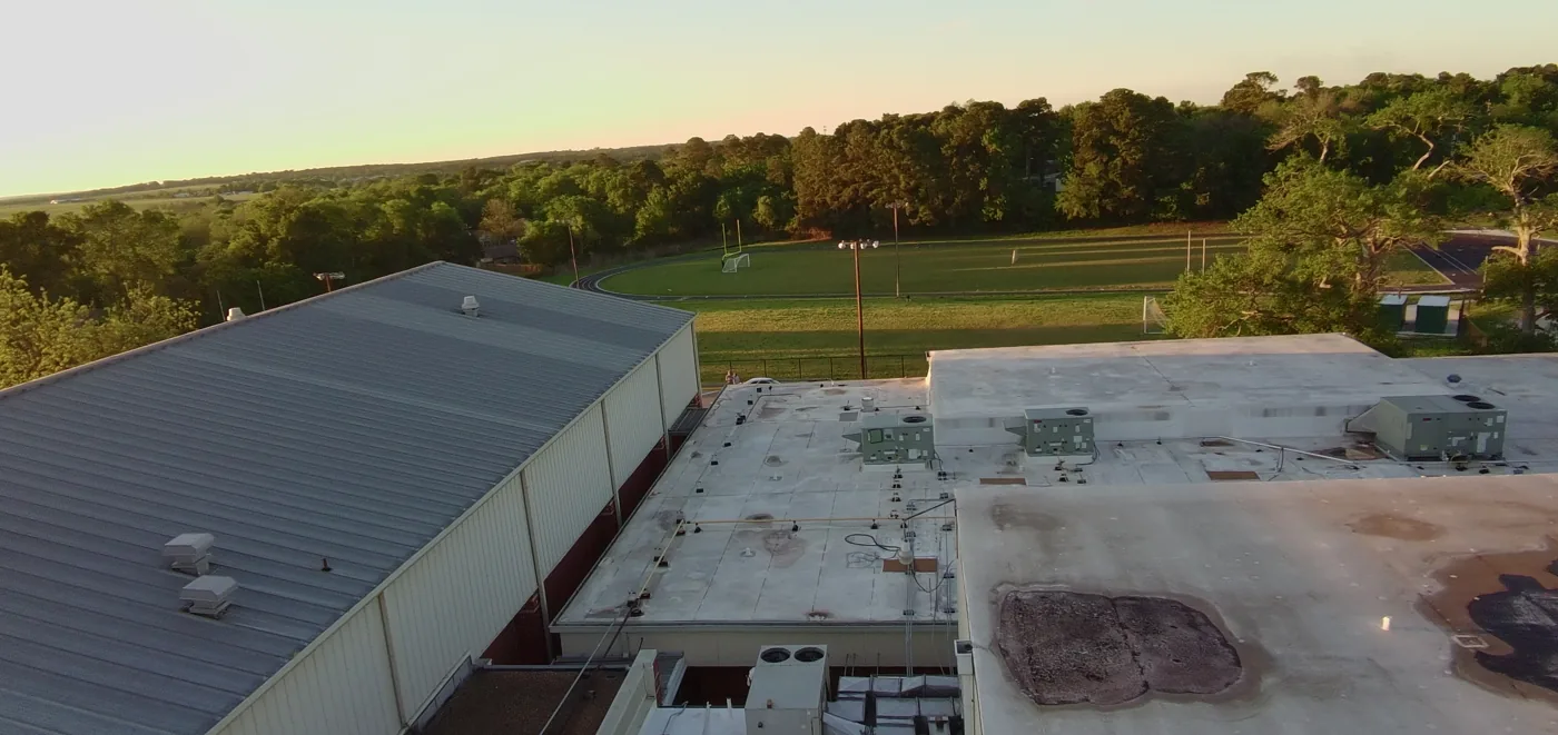 Drone view of a stained, aged school band hall roof in Huntsville before restoration