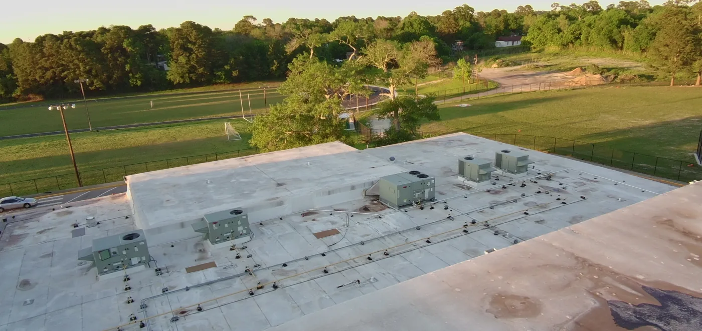Close drone view of rooftop units and stained roof surface before restoration
