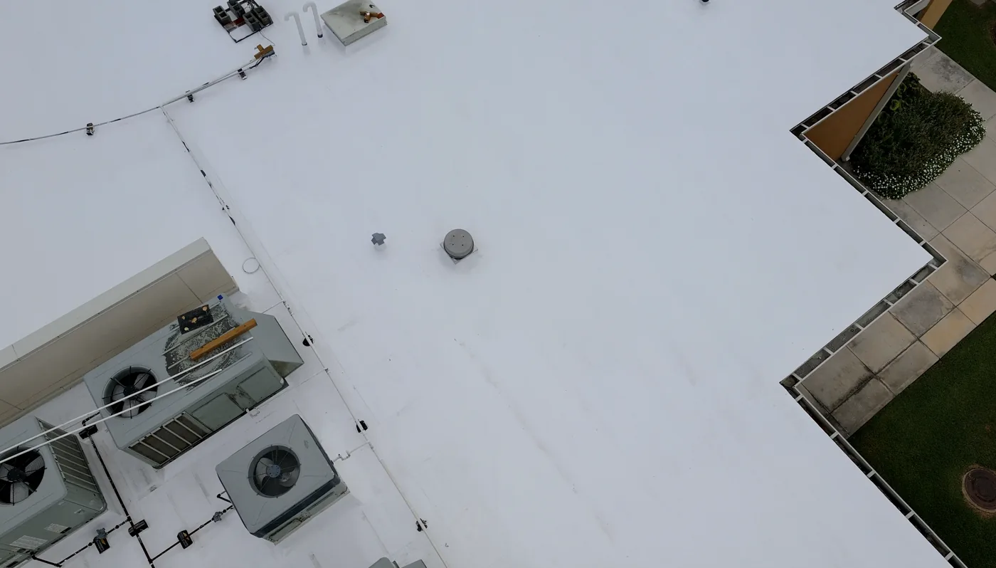 Drone view of a finished white silicone-restored roof around rooftop units