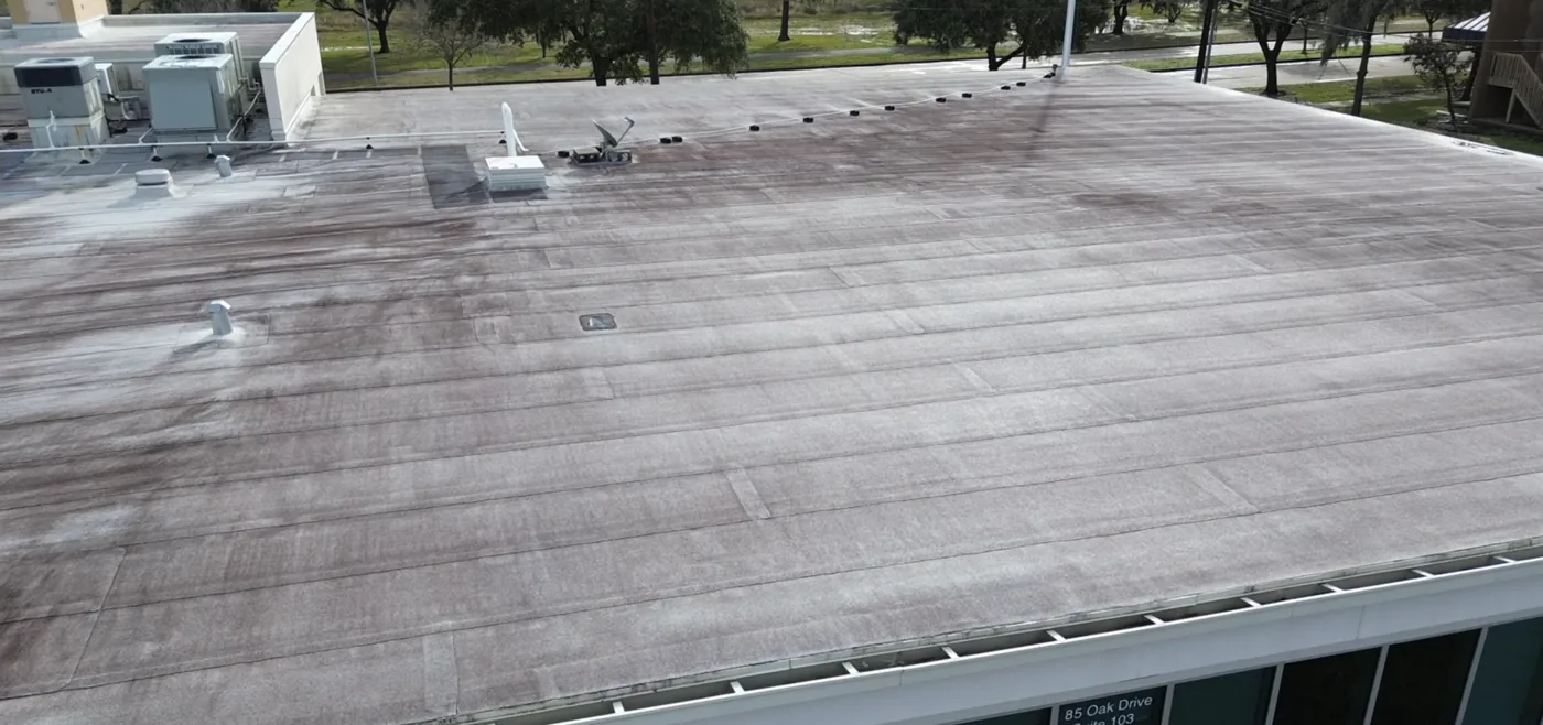 Aged modified bitumen roof surface with streaking before restoration