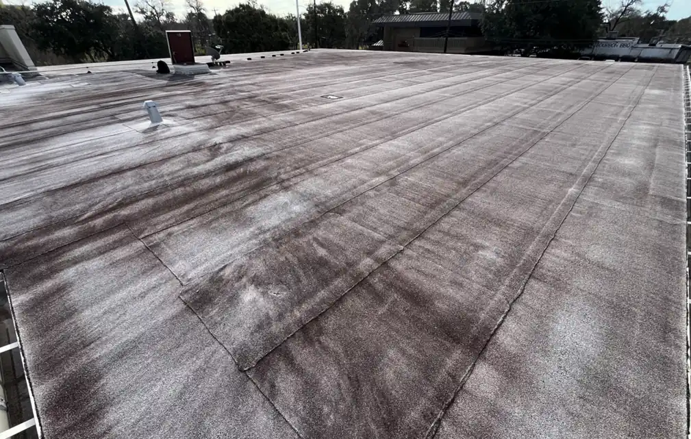 Weathered, stained modified bitumen roof on a bank building in the Lake Jackson area before restoration
