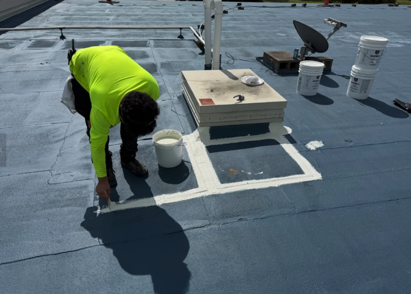 Ramtech crew member sealing around rooftop equipment
