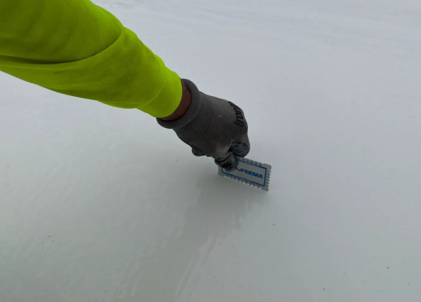 Gloved hand checking wet-film thickness on a freshly applied restoration layer
