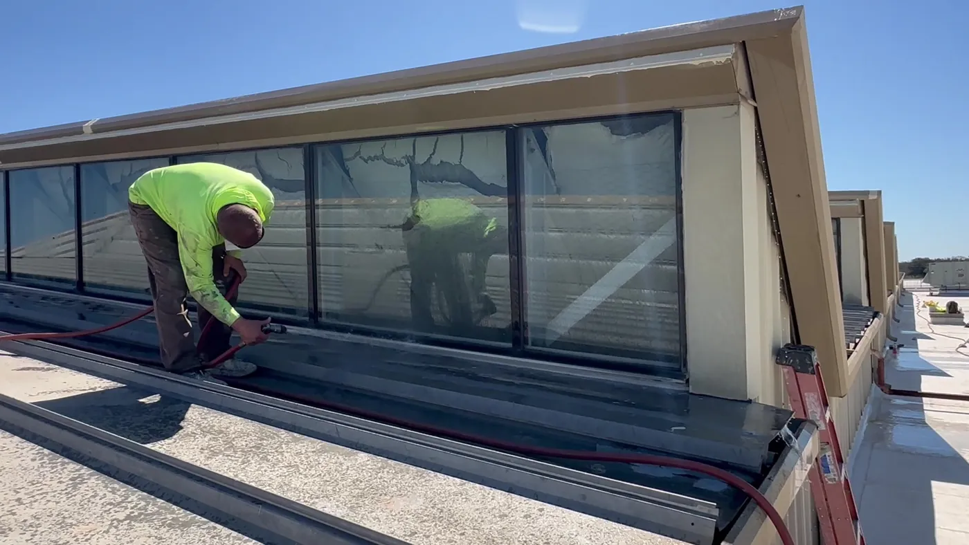 Ramtech technician water-testing the repaired skylight glazing on a metal roof
