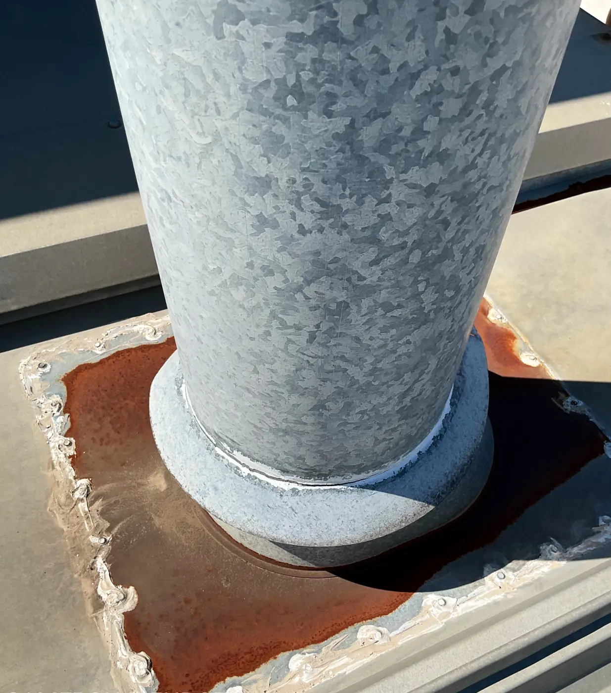 Corroded base around a pipe penetration on a metal roof