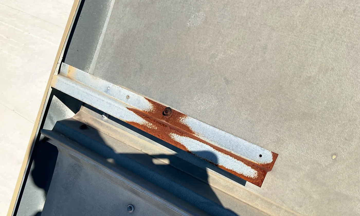 Rusted flashing strip and fasteners on a metal roof