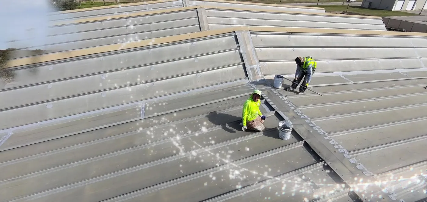 Ramtech crew pressure-washing an aged standing seam metal roof before repairs at a technical college building in Waco
