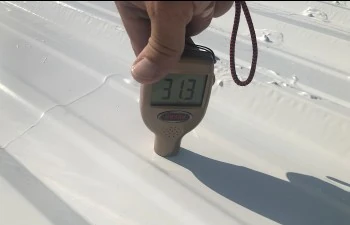 A handheld gauge being used on the restored metal roof surface